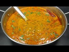 a large pot filled with soup on top of a stove next to a spatula