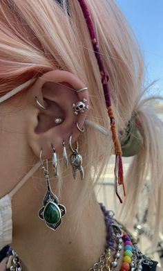 a close up of a person with ear piercings on their ears and wearing jewelry