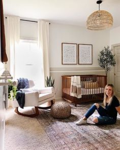 a woman sitting on the floor in front of a baby crib