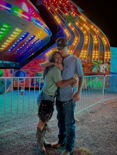 a man and woman hugging in front of a carnival ride