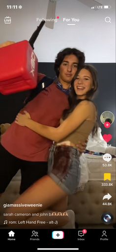 a man and woman hugging each other in front of a bed with luggage on it