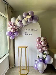 the balloon arch is decorated with purple, lavender and white balloons