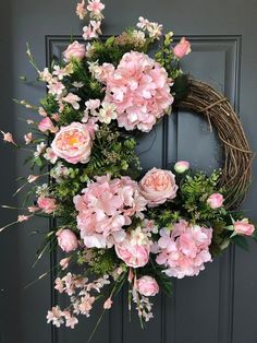 a wreath with pink flowers and greenery on the front door