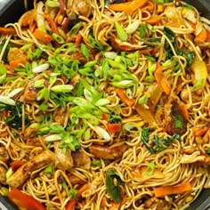 a wok filled with noodles, vegetables and meat