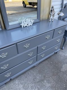 a dresser with a mirror on it and a zebra figurine next to it