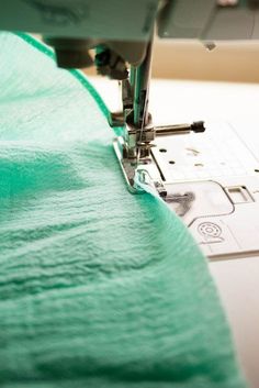 the sewing machine is working on the green material that has been sewn together with it's needle