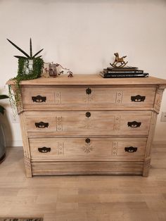 a wooden dresser with many drawers and plants on top