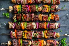 several skewered meats and vegetables are arranged in rows on a gray surface