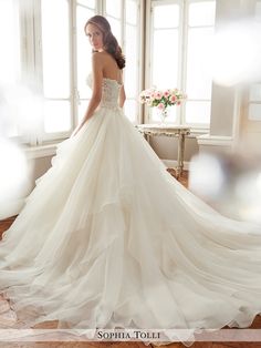 a woman in a wedding dress standing by a window