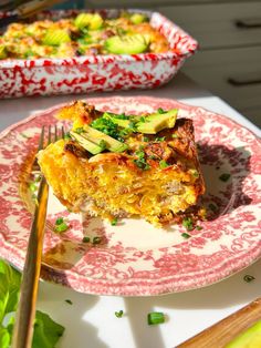 a piece of quiche on a pink and white plate with a fork next to it