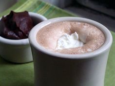 two white cups filled with food on top of a green tablecloth covered table next to each other