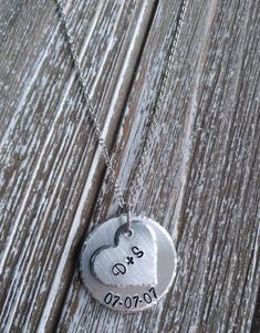 two heart shaped pendants on a wooden surface with the word love written in black ink