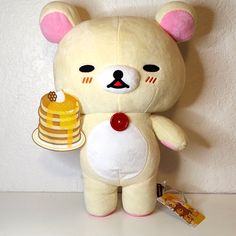 a teddy bear holding a stack of pancakes and a honey jar with a bee on it