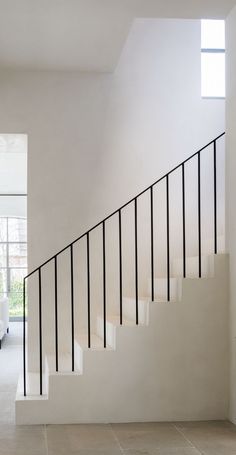 a white staircase with black handrails in a modern style home, leading up to the second floor