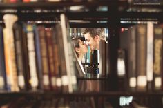 a man and woman kissing in front of a bookshelf