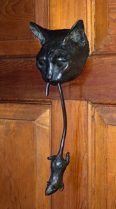 a metal cat and mouse hook on a wooden door