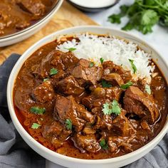 two bowls filled with meat and rice on top of a wooden table