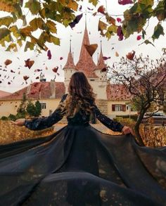 a woman standing in front of a castle with her arms spread out to the side