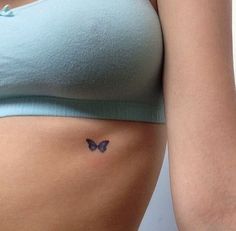 a woman's stomach with a butterfly tattoo on the side of her belly,