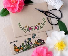 two cards with flowers and scissors next to them