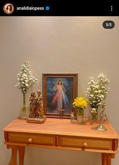 a wooden table topped with vases and flowers next to a painting on the wall