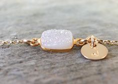 A small white druzy crystal set in gold plated bezel and attached to a delicate gold filled chain with a tiny dangling gold filled initial tag. The druzy has a natural raw crystal top with a light sparkly coating that have a soft shimmer. They are so dainty and beautiful. Great gift for your sister, bridesmaids, friends or for yourself. You and your bridesmaids/maid of honor will love this simply, but elegant bracelet on your wedding day. DETAILS - Gold filled rolo chain with 6mm spring ring cla Adjustable Gold Jewelry For Bridesmaid, White Jewelry With Adjustable Chain For Bridesmaid Gift, Elegant Gold Bridesmaid Bracelets, Dainty Gold Bridesmaid Jewelry, Bridesmaid Jewelry Gold, Gold Bridesmaid Jewelry, Initial Bracelet Gold, Schmuck Gold, Gold Pearl Bracelet