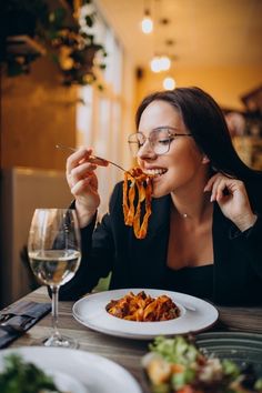 a woman sitting at a table eating spaghetti