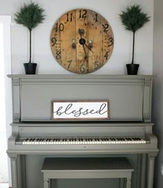 there is a clock on the wall above an old piano that has been decorated with plants