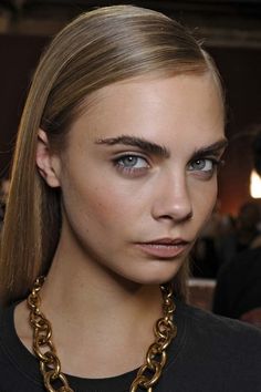 a model with blonde hair and blue eyes wearing a gold chain necklace