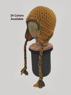 a crocheted hat with braids is shown on top of a black container