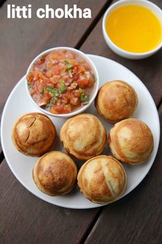 there are several small rolls on the plate next to a bowl of soup and a cup of orange juice