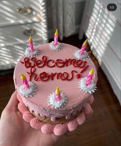 someone holding up a pink birthday cake with candles on it that says, become hero