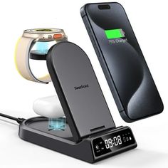 an electronic device charging with a watch and cell phone in the back ground next to it