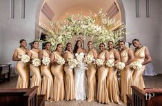 a group of women standing next to each other in front of a white flower arch