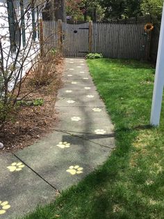 a sidewalk with yellow paw prints on it next to a fence and trees in the background