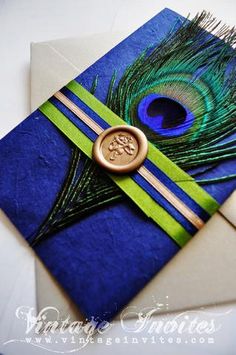 a blue and green wedding card with a wax stamp on the front that has a peacock feather