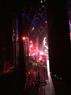 an empty stage is lit up at night with bright lights on the floor and chairs