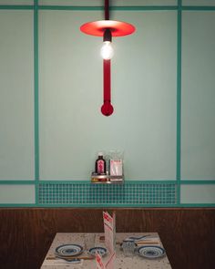 a table with plates, cups and utensils on it next to a light fixture