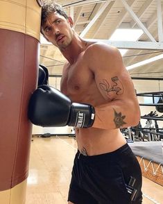 a shirtless man standing next to a punching bag