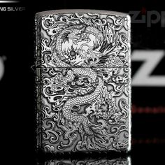 a zippo lighter with a dragon design on the front and side, in silver