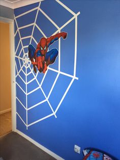 a spiderman mural painted on the side of a blue wall in a child's room