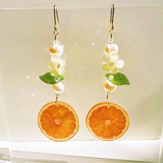 Juicy and delicious, these orange slice dangle earrings, crafted with 18k gold-filled ear wire, embody the essence of fairycore and perfect for the woodland gardener, these cute citrus-inspired resin jewelry pieces are ideal botanical gifts for her. 🍊 🍊 🍊 ITEM SPECIFICATIONS: - Material: Crafted with care using premium resin, natural freshwater pearl and glass beads. - Size: A total length of 2.7 inches. - Ear Wire: 18k gold filled ear wire hook. - 100% Handmade. ❤️ Each item is meticulously handcrafted, ensuring a unique and distinctive piece of jewelry. Please note that due to the handmade nature of our products, slight variations in shape and pattern may occur. 🚀 Processing time may vary depending on the intricate crafting process. As for shipping, our shipping service generally del Kawaii Fruit, Fruit Gifts, Cardboard Gift Boxes, Fruit Earrings, Orange Slices, Ear Wire, Resin Jewelry, Handmade Natural, Jewelry Pieces