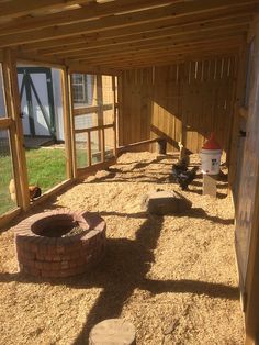 the inside of a chicken coop with an open door and brick fire pit in it