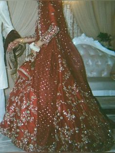 a man and woman standing next to each other in wedding outfits, dressed in red with gold sequins