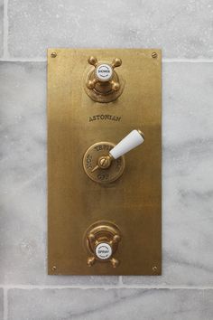 a brass plate with thermostaer on it's side and two white knobs