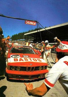 a red and white race car is parked in front of a crowd with people around it