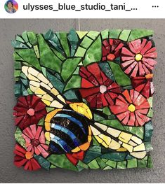 a piece of art made out of stained glass with flowers and a bee on it