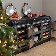 a christmas tree is in front of an oven with food on the stove and plates under it