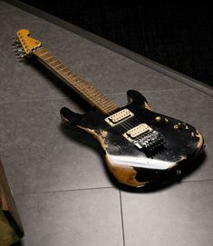 an old black and gold guitar laying on the floor