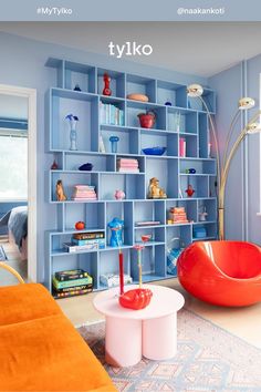 a living room filled with lots of blue bookshelves and orange chairs next to a white coffee table